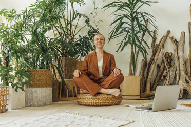 Smiling businesswoman meditating by laptop at work place - VPIF04170