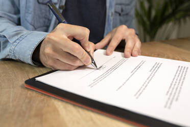 Geschäftsmann macht Unterschrift auf Vertrag am Schreibtisch im Büro - JCCMF02685
