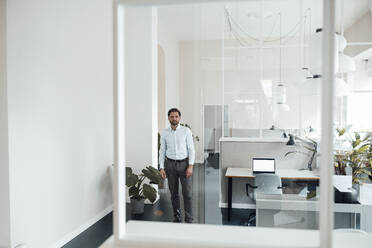 Businessman standing by desk in office - GUSF05959