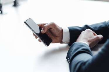 Geschäftsmann mit Smartphone auf dem Schreibtisch im Büro - GUSF05999