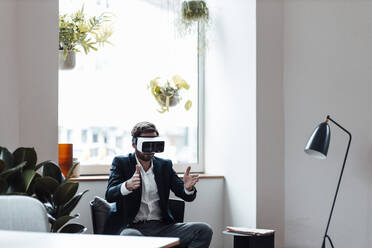 Male entrepreneur gesturing while using virtual reality headset at office - GUSF06005