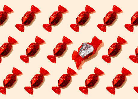 Pattern of rows of red wrapped candies with single empty wrapper - FLMF00492