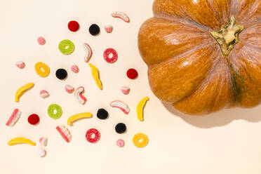 Studioaufnahme von rohem Kürbis und verschiedenen Halloween-Süßigkeiten - FLMF00498