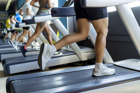 Male and female athletes running on treadmill in gym - MPPF01752