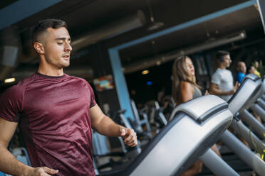 Male and female athletes running on treadmill at gym - MPPF01754