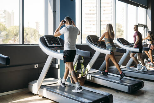 Male and female athlete exercising on treadmill at health club - MPPF01758