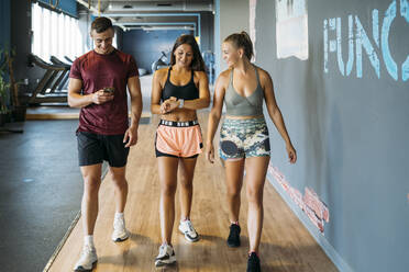 Mann benutzt Mobiltelefon beim Spaziergang mit Freundinnen im Fitnessstudio - MPPF01768