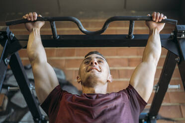 Muskulöser Mann schaut weg, während er im Fitnessstudio trainiert - MPPF01771