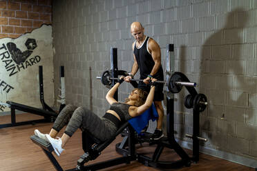 Mann hilft Frau beim Gewichtheben im Fitnessstudio - MPPF01785