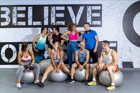 Lächelnde männliche und weibliche Athleten schauen sich im Fitnessstudio an - MPPF01825