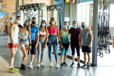 Male and female athletes wearing protective face masks standing at gym - MPPF01829
