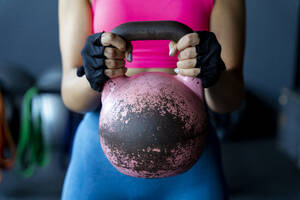 Junge Sportlerin hält Kettlebell im Fitnessstudio - MPPF01834