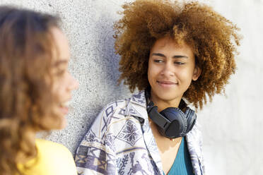 Afro young woman with female friend against wall - IFRF00759