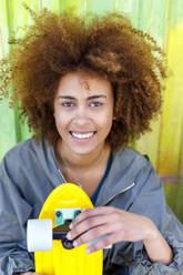Afro junge Frau mit gelbem Skateboard - IFRF00775