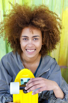 Afro junge Frau mit gelbem Skateboard - IFRF00775