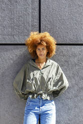 Afro young woman standing in front of wall on sunny day - IFRF00778