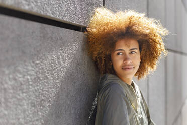 Young Afro woman contemplating in front of wall - IFRF00779