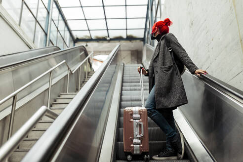 Redheaded woman on escalator at railway station - MRRF01226