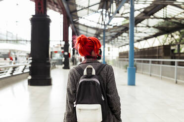 Redheaded woman with backpack on railroad platform during COVID-19 - MRRF01228