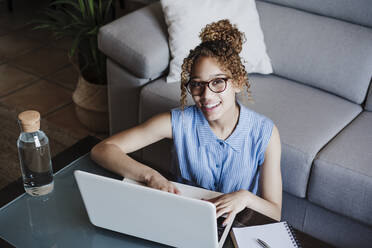 Lächelnde Frau, die zu Hause am Laptop arbeitet - EBBF03866