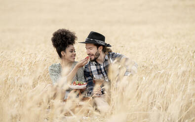 Girlfriend feeding strawberry to boyfriend during picnic - JCCMF02774