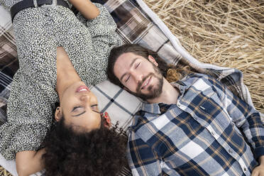 Girlfriend and boyfriend with eyes closed resting on blanket - JCCMF02783