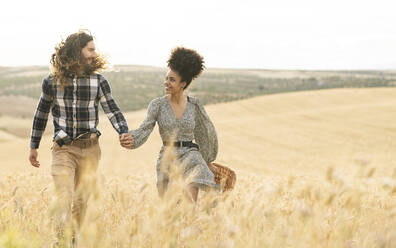 Paar, das sich beim Gehen auf einem Weizenfeld ansieht - JCCMF02792