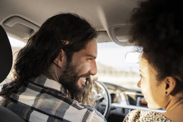 Girlfriend looking at smiling boyfriend in car - JCCMF02807