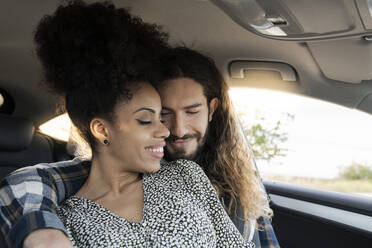 Smiling boyfriend with arm around girlfriend in car - JCCMF02809