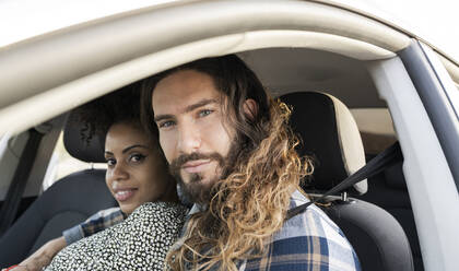 Mid adult couple staring while sitting in car - JCCMF02810