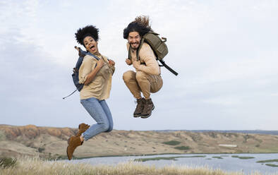 Carefree couple with backpacks jumping together - JCCMF02816