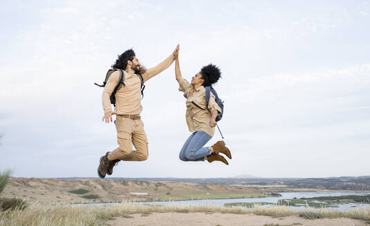 Freundin und Freund geben sich beim Springen gegenseitig die Hand - JCCMF02818