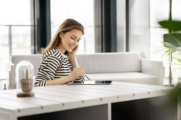 Smiling female entrepreneur using graphics tablet at table in office - PESF02867