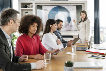 Geschäftsfrau schaut auf männliche und weibliche Kollegen, die im Büro an Grafiktabletts arbeiten - PESF02890