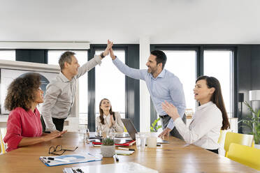 Fröhliche weibliche Fachkräfte klatschen, während Geschäftsleute im Büro High-Five machen - PESF02904