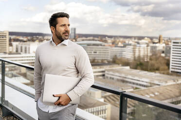 Geschäftsmann mit Laptop auf dem Balkon eines Büros - PESF02926