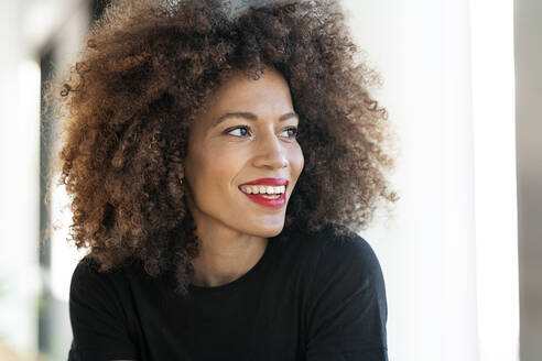 Smiling businesswoman with frizzy hair looking away in office - PESF02947