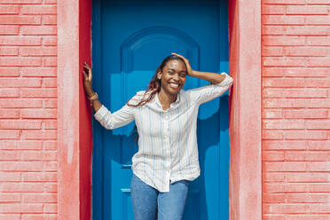 Glückliche Frau in der Tür stehend an einem sonnigen Tag - JRVF00945