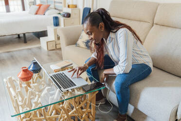 Smiling woman using laptop at home - JRVF00950