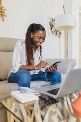 Lächelnde Frau mit Mobiltelefon im Wohnzimmer zu Hause - JRVF00953