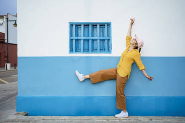 Cheerful woman dancing by wall - RCPF01172