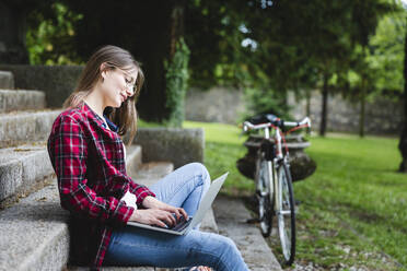 Junge Frau benutzt Laptop in einem öffentlichen Park - MCVF00884