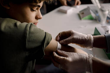 Female healthcare worker applying bandage to boy's arm - MASF23818