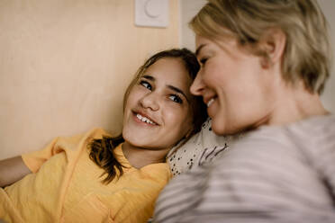 Lächelndes Mädchen schaut Mutter im Schlafzimmer an - MASF23831