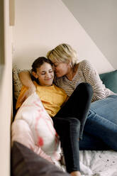Smiling mother and daughter lying on bed at home - MASF23837