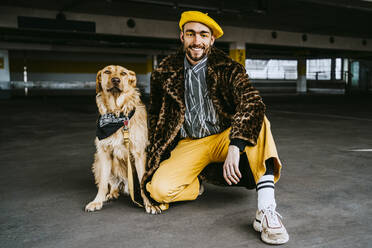 Full length of smiling young man with golden retriever in parking garage - MASF23881