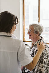 Female healthcare worker comforting senior patient at medical clinic - MASF23906