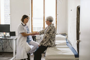 Female doctor checking pulse of senior patient at medical clinic - MASF23908