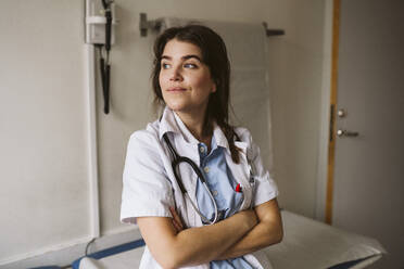 Female medical expert standing with arms crossed looking away - MASF23919