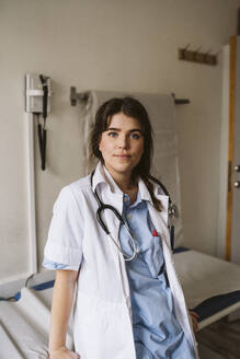 Porträt einer Mitarbeiterin des Gesundheitswesens, die sich auf einen Untersuchungstisch in einer medizinischen Klinik stützt - MASF23922